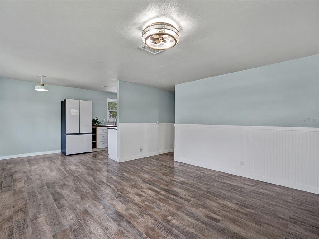 A room with light blue walls, white wainscoting, and wood-look flooring features a ceiling fan — 5633 ESSEX WAY, NEW PORT RICHEY, FL