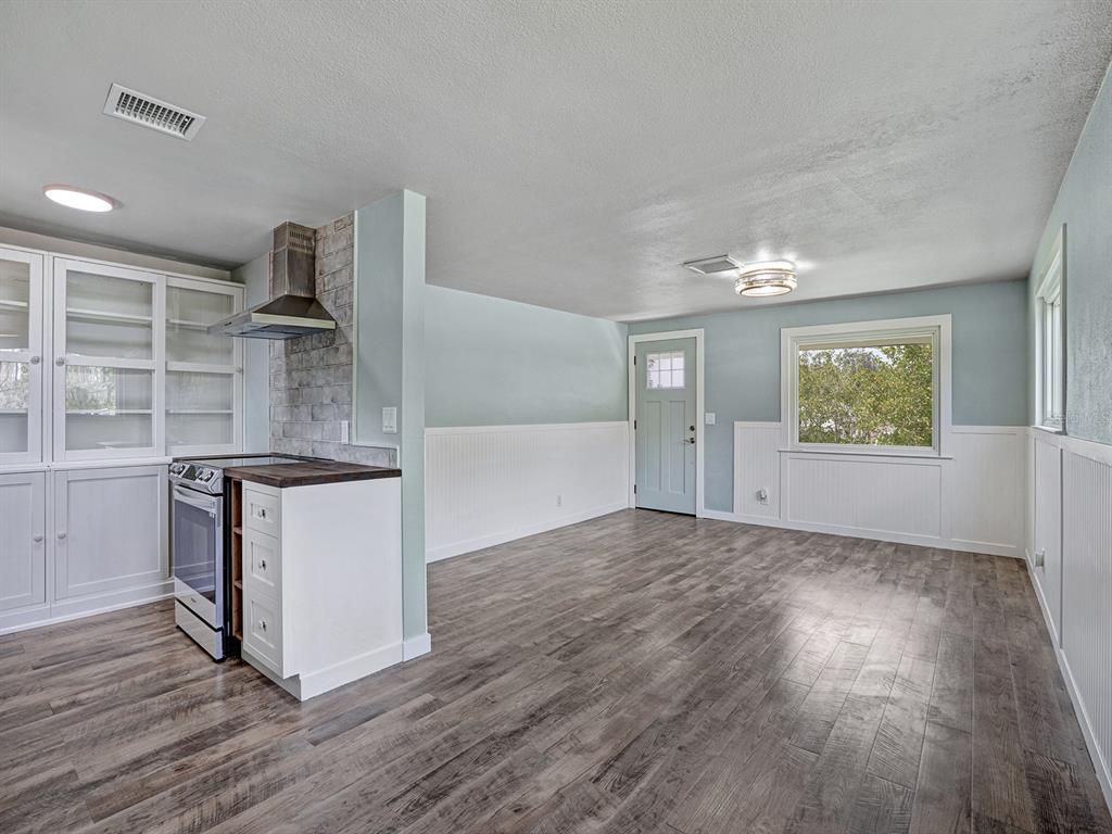 A kitchen and dining area with light blue walls, white wainscoting, and wood-look flooring — 5633 ESSEX WAY, NEW PORT RICHEY, FL