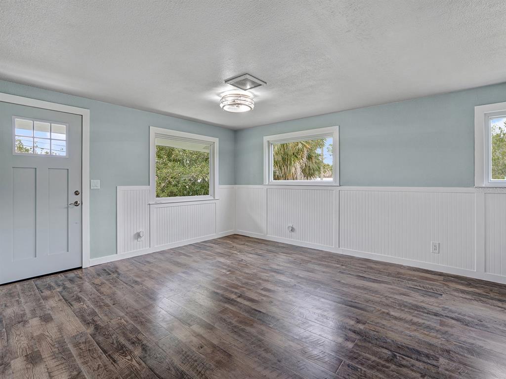 An empty room features light blue walls, white wainscoting, and dark wood-look flooring — 5633 ESSEX WAY, NEW PORT RICHEY, FL