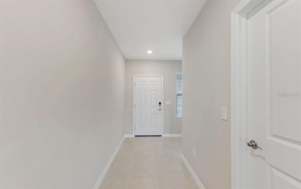 A bright entryway features light-colored tile flooring, gray walls, and a white front door — 18505 CRONIN SAND LANE, NORTH FORT MYERS, FL