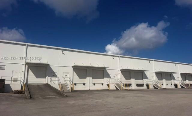 A white industrial warehouse building features multiple loading dock doors and concrete ramps — 11701 NW 102nd Rd # 10, Medley FL 33178, MEDLEY, FL