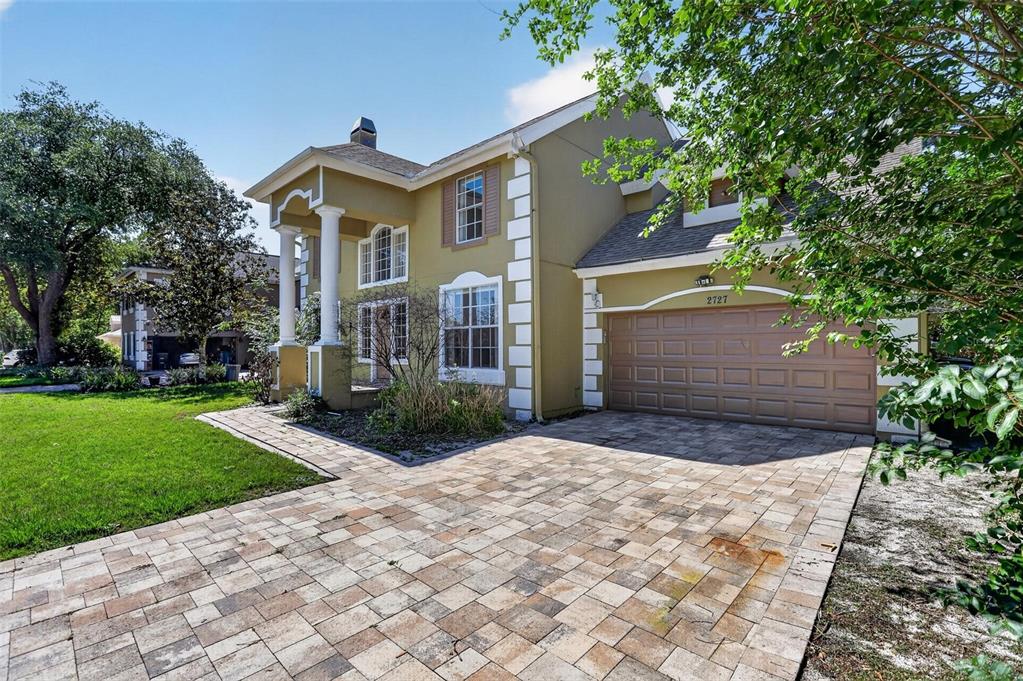 A two-story house with a tan stucco exterior, white columns, and a paved driveway — 2727 RUNNING SPRINGS LOOP, OVIEDO, FL