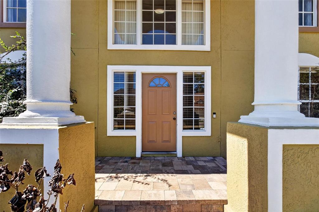 A tan house exterior features a brown front door flanked by sidelights and white columns — 2727 RUNNING SPRINGS LOOP, OVIEDO, FL