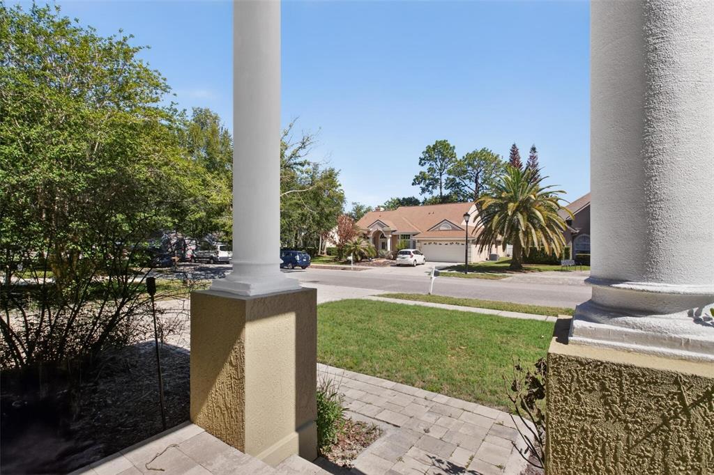 A view from a porch with two white columns looking out toward a suburban street — 2727 RUNNING SPRINGS LOOP, OVIEDO, FL