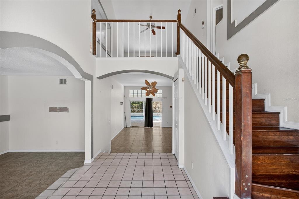 A foyer with tiled floors leads to a staircase and an open living area beyond — 2727 RUNNING SPRINGS LOOP, OVIEDO, FL