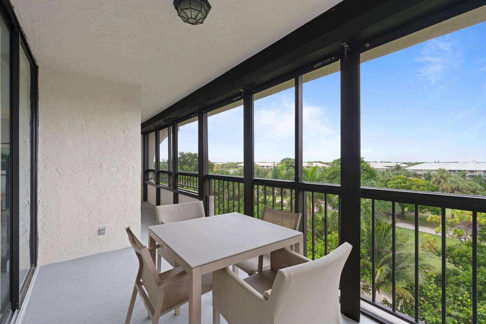 A screened-in balcony features a dining table and chairs overlooking a lush, tropical landscape — 6420 Boca Del Mar Drive # 601, Boca Raton FL 33433, BOCA RATON, FL