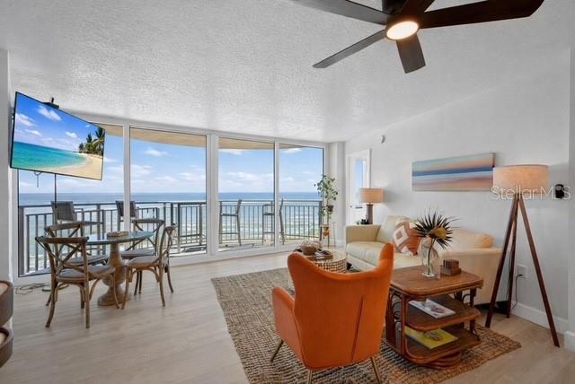 A living room features a dining area, an orange armchair, and a balcony overlooking the ocean — 2625 S ATLANTIC AVENUE UNIT 14NE, DAYTONA BEACH, FL