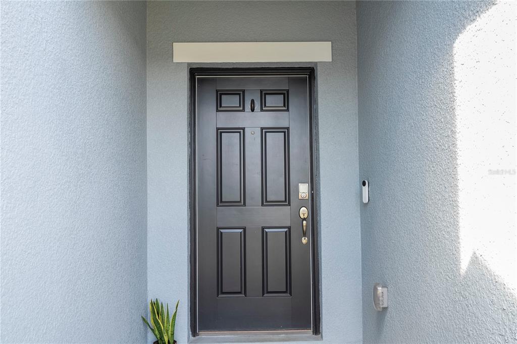 A black front door with a smart lock is set within a light blue entryway — 5166 TUSCANY LANE, DAVENPORT, FL