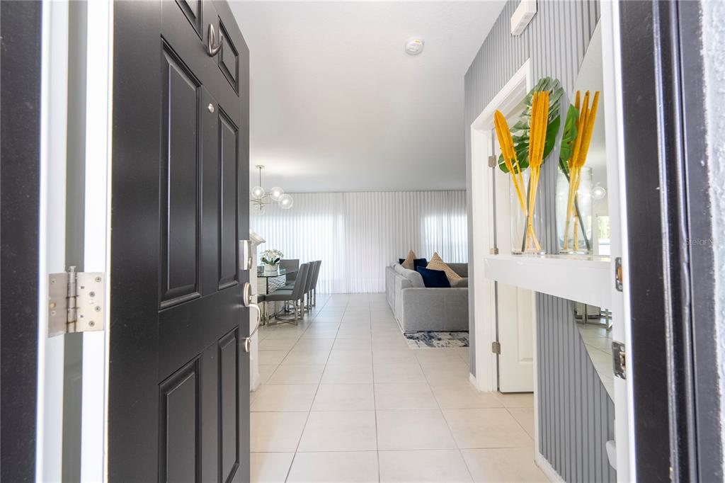 An open front door reveals a tiled entryway leading into a living and dining area — 5166 TUSCANY LANE, DAVENPORT, FL