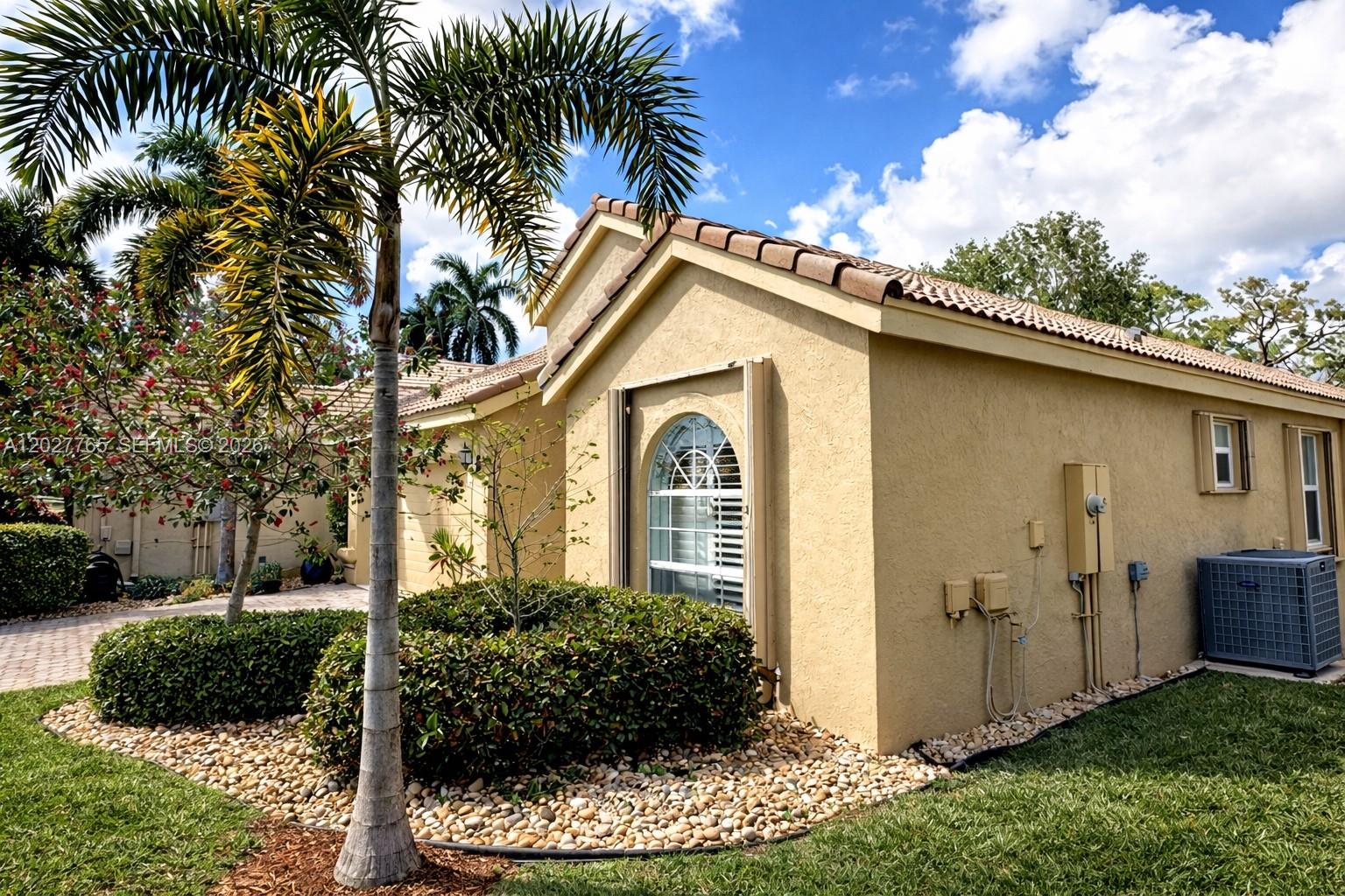 A tan stucco house with a tiled roof, arched window, and palm tree in the front — 3933 Diamond Palladium Ter, Boynton Beach FL 33436, BOYNTON BEACH, FL