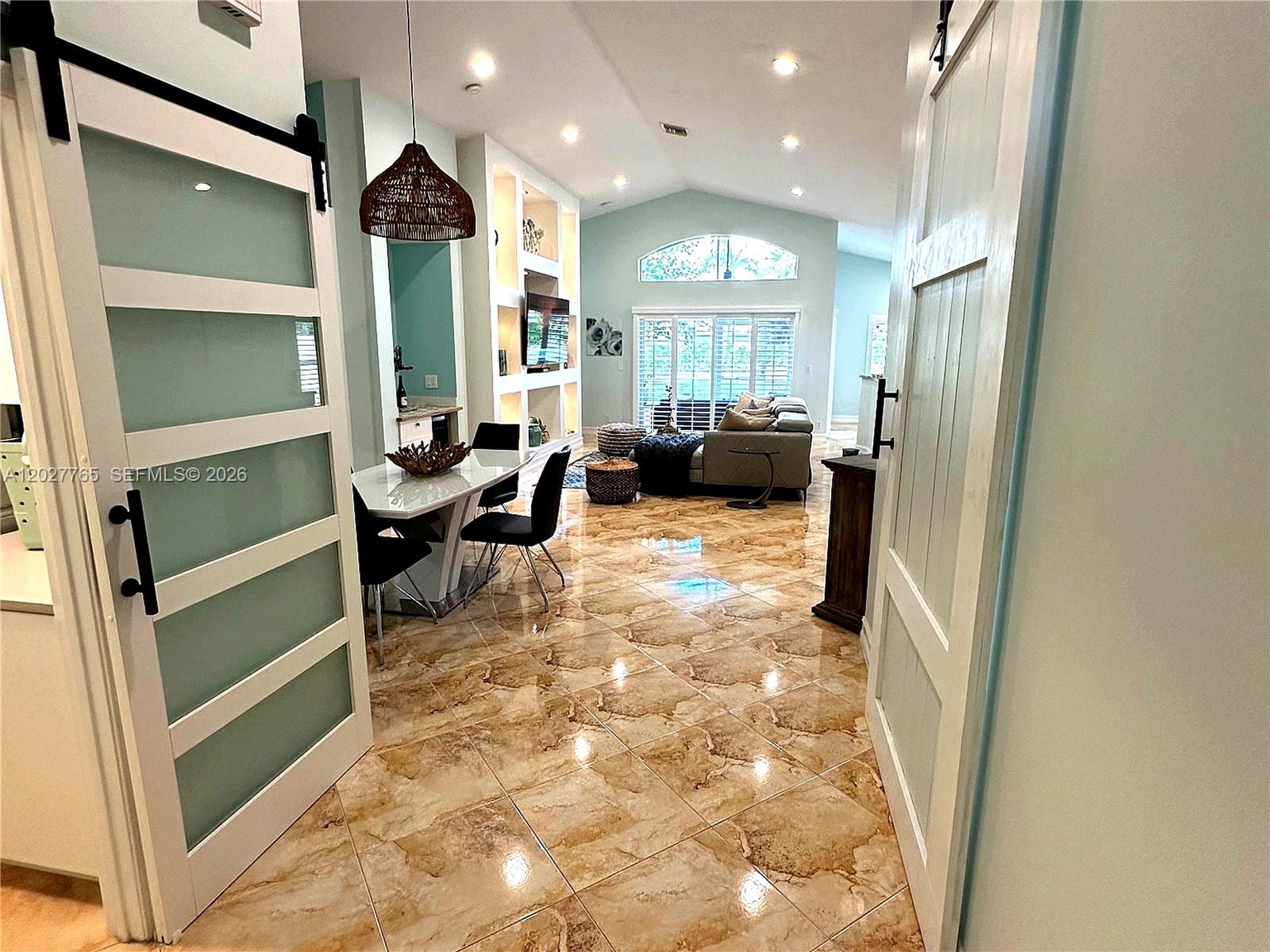 A dining area and living room feature light blue walls, tile floors, and sliding doors — 3933 Diamond Palladium Ter, Boynton Beach FL 33436, BOYNTON BEACH, FL