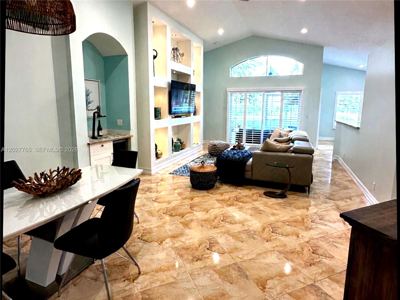 A living room and dining area feature light blue walls, built-in shelving, and marble flooring — 3933 Diamond Palladium Ter, Boynton Beach FL 33436, BOYNTON BEACH, FL