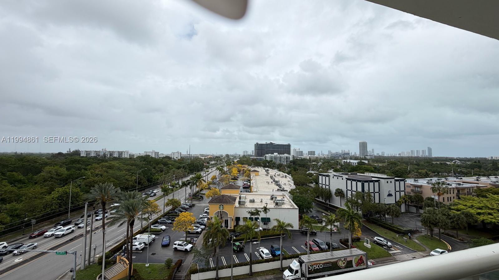 An elevated view shows a commercial plaza with a Starbucks, parking lot, and surrounding trees — 13499 Biscayne Blvd # 805, North Miami FL 33181, NORTH MIAMI, FL