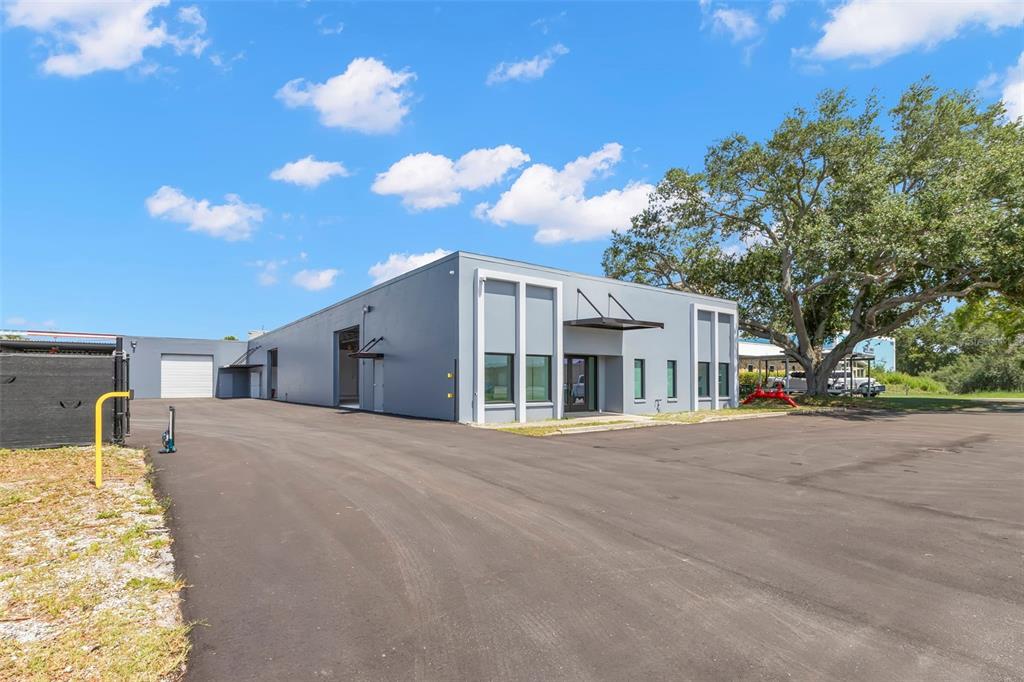 A modern gray industrial building with a paved parking lot and a large oak tree — 1195 KAPP DRIVE UNIT 1, CLEARWATER, FL