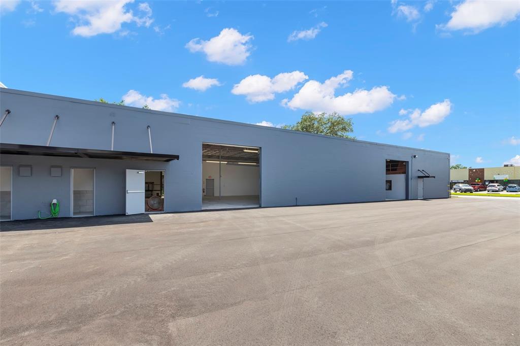 A gray industrial building features a large open bay door and a paved parking lot — 1195 KAPP DRIVE UNIT 1, CLEARWATER, FL
