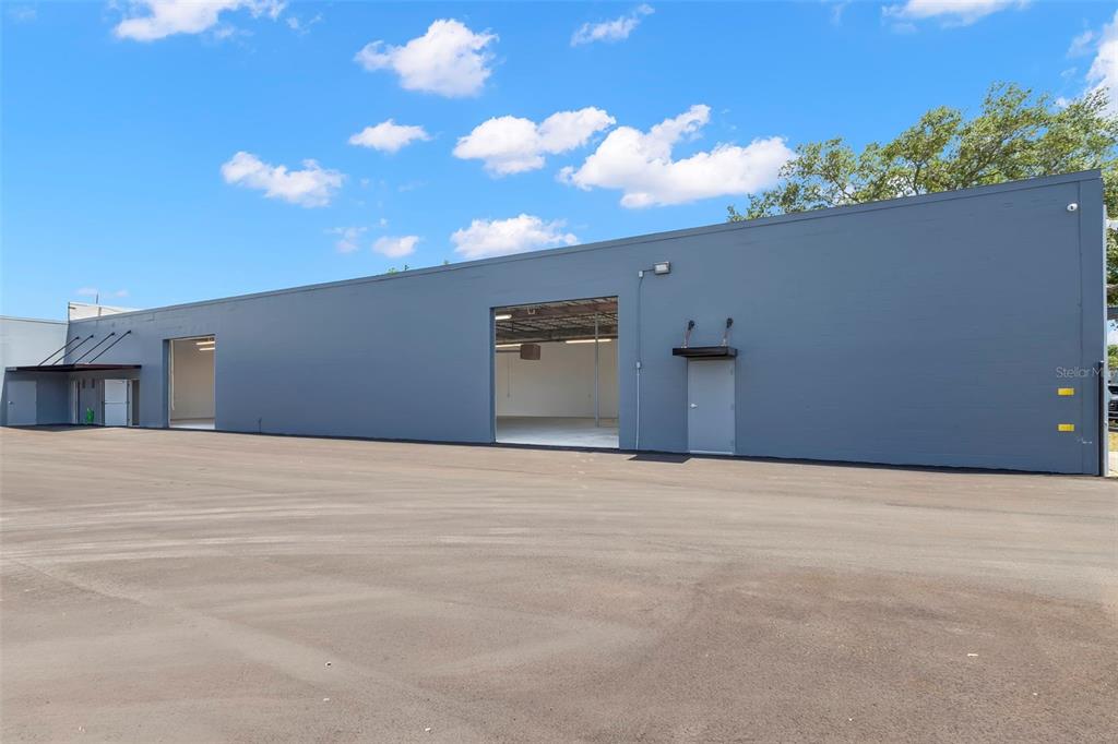 A gray industrial warehouse building features large open bays and a paved parking lot — 1195 KAPP DRIVE UNIT 1, CLEARWATER, FL