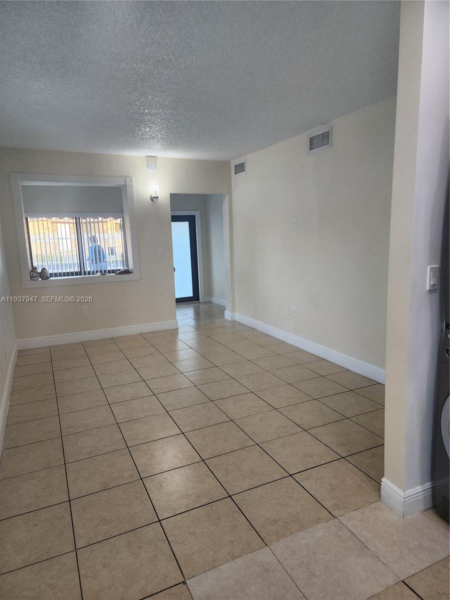 An empty room features beige tile flooring, white walls, and a window looking outside — 310-312 SW 36th Ave, Miami FL 33135, MIAMI, FL