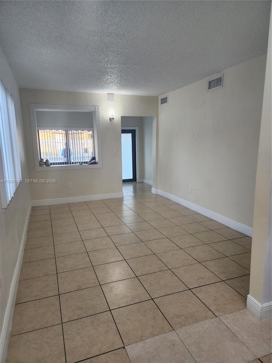 An empty room features beige tile flooring, white walls, and a window with blinds — 310-312 SW 36th Ave, Miami FL 33135, MIAMI, FL