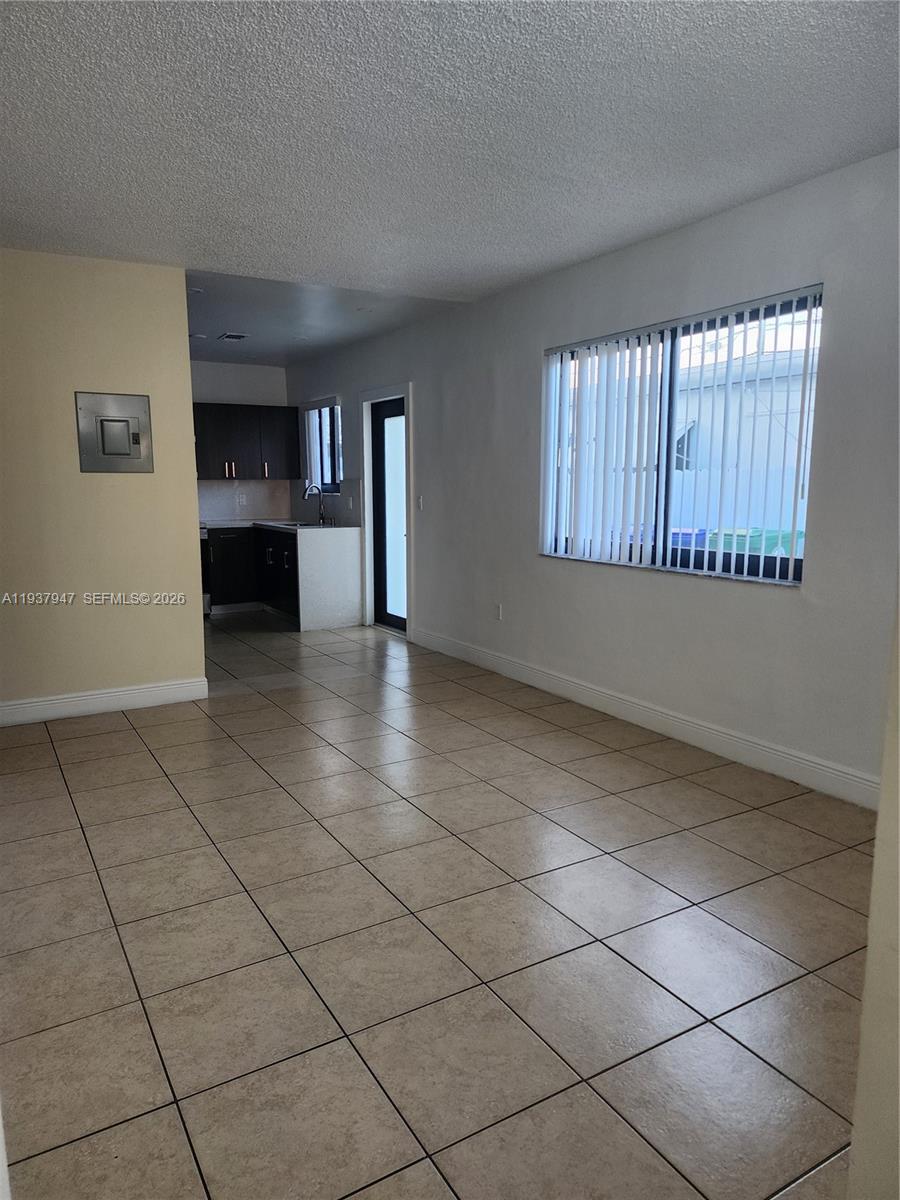This room features beige tile flooring, white walls, and an adjacent kitchen area — 310-312 SW 36th Ave, Miami FL 33135, MIAMI, FL