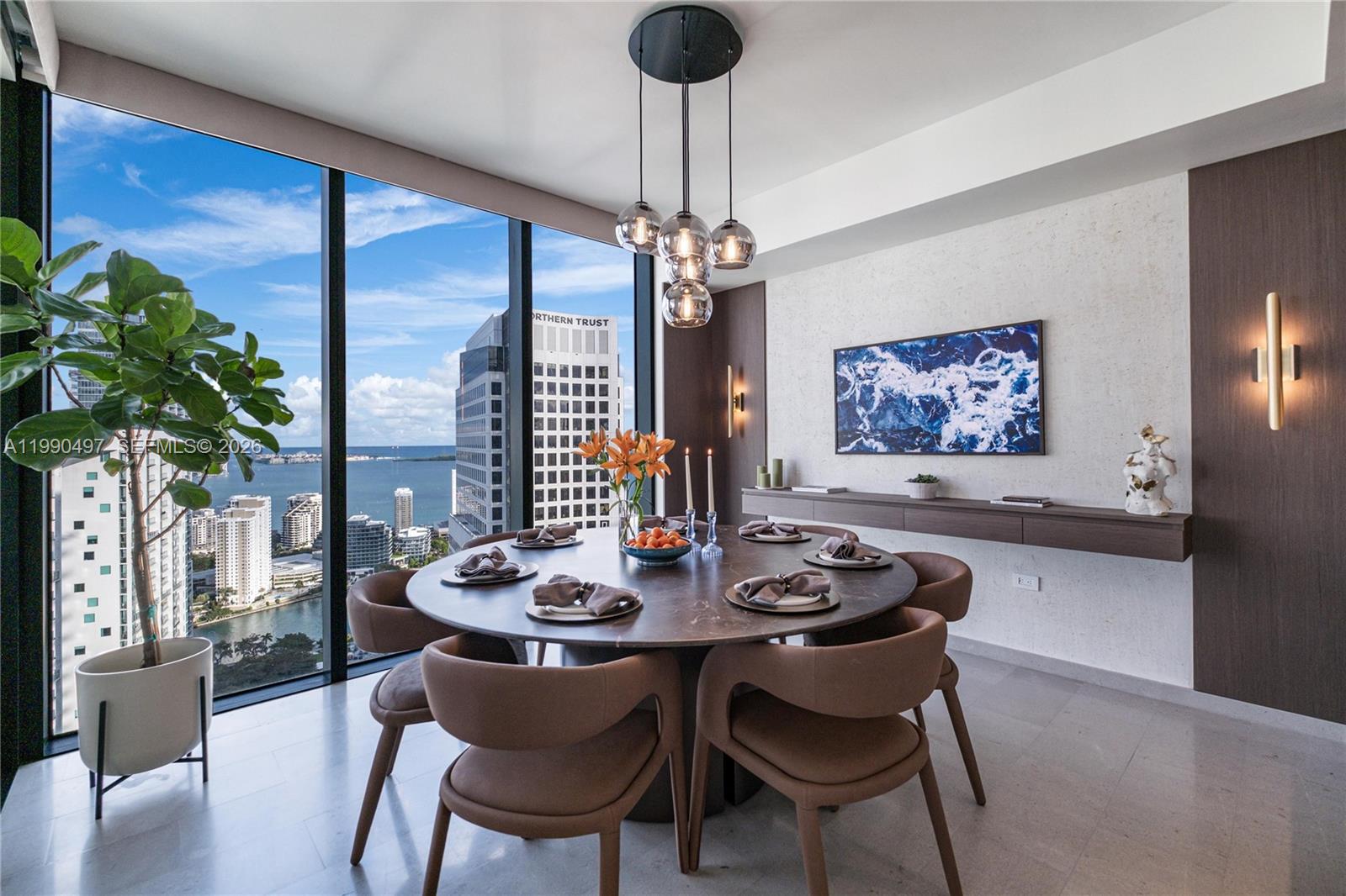 A modern dining room features a round marble table, pendant lighting, and floor-to-ceiling city views — 68 SE 6th St # 3711, Miami FL 33131, MIAMI, FL