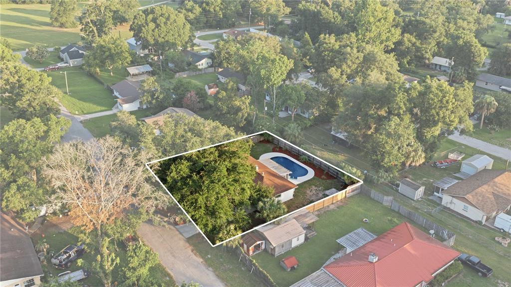 An aerial view shows a house with a swimming pool and large trees in the yard — 5611 NE 5TH PLACE, OCALA, FL