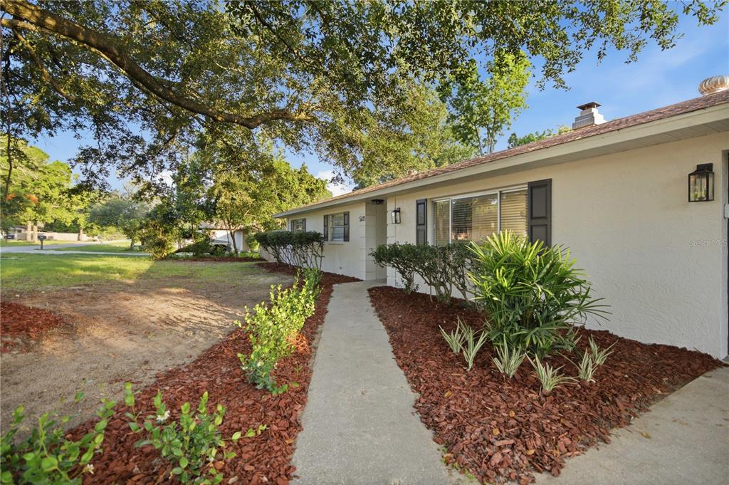 A concrete walkway leads to the front entrance of a single-story house with white siding — 5611 NE 5TH PLACE, OCALA, FL