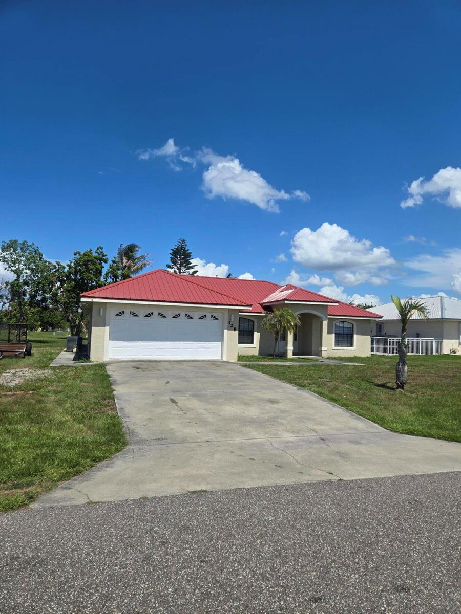 A single-story house with a red metal roof and a concrete driveway — 328 W Sugarland Circle, Clewiston FL 33440, CLEWISTON, FL