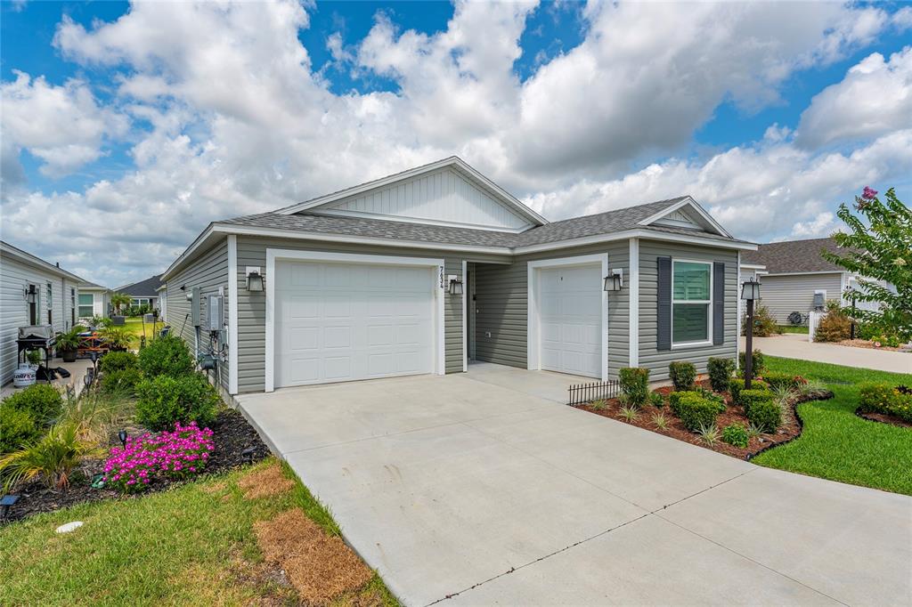 A single-story house with gray siding, a two-car garage, and a landscaped front yard — 7634 CHERYL COURT, THE VILLAGES, FL