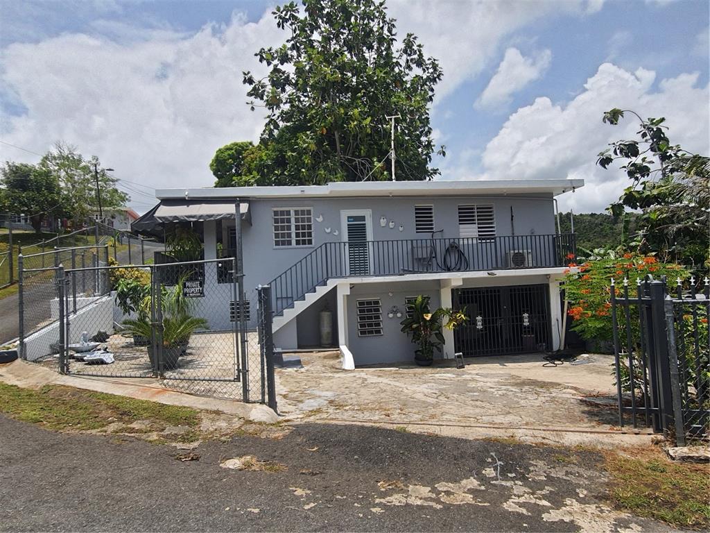 A two-story gray house with a metal fence, outdoor staircase, and a concrete driveway — 2-A RIO CANAS WARD, LA BARRA COMMUNITY LOT 199, CAGUAS, PR