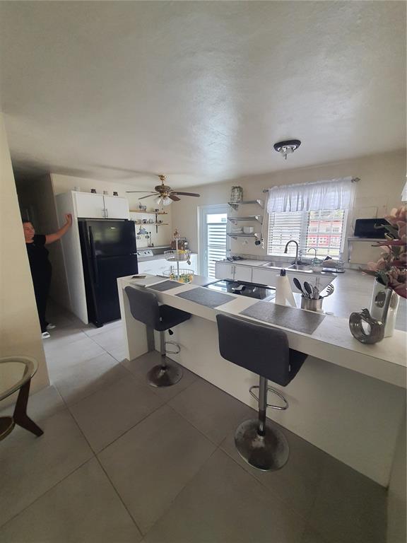 A kitchen features a black refrigerator, a breakfast bar with two stools, and white cabinetry — 2-A RIO CANAS WARD, LA BARRA COMMUNITY LOT 199, CAGUAS, PR