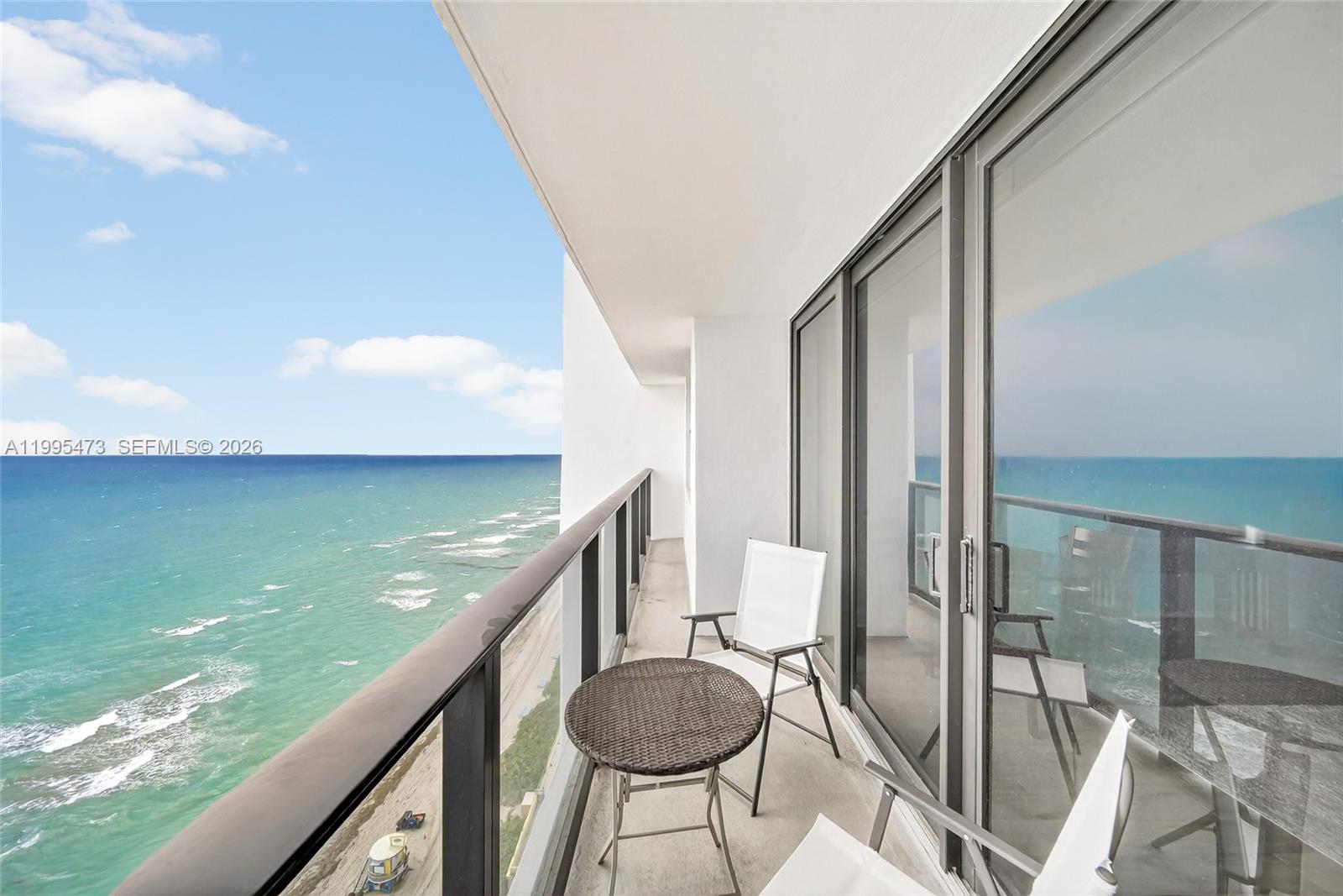 A balcony with a small table and chairs overlooks the ocean and beach — 2301 S Ocean Dr # 2302, Hollywood FL 33019, HOLLYWOOD, FL