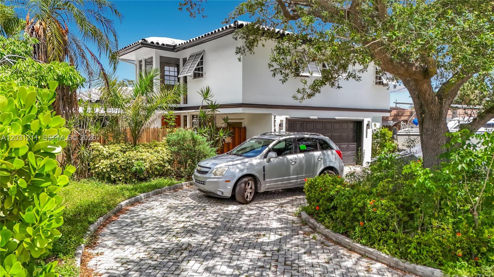 A silver SUV is parked on a paved driveway in front of a two-story house — 2216 NE 18th Ave, Wilton Manors FL 33305, WILTON MANORS, FL