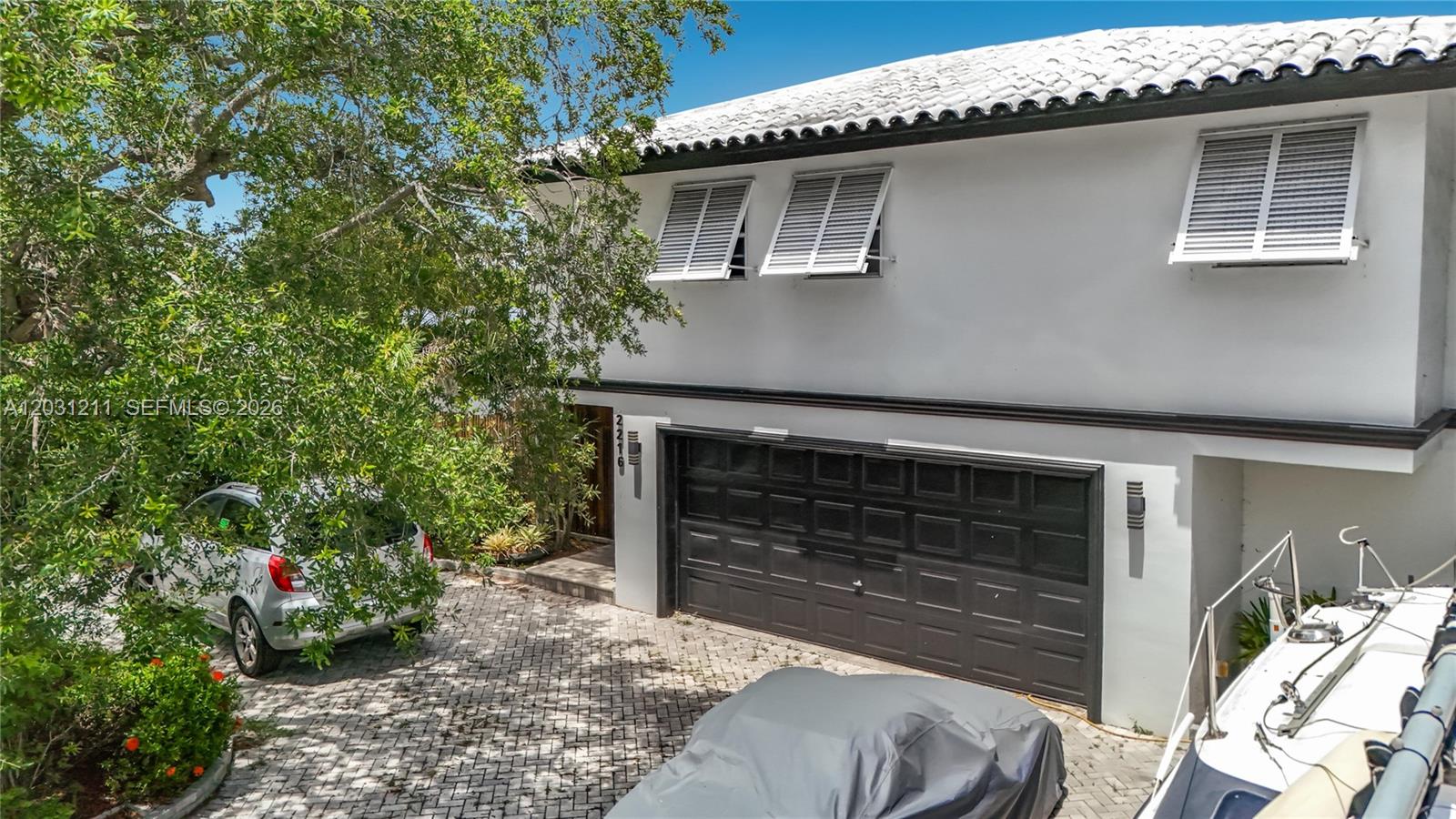 A two-story white house with a black garage door and a paved driveway — 2216 NE 18th Ave, Wilton Manors FL 33305, WILTON MANORS, FL