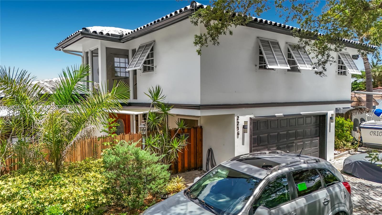 A two-story white house with a garage, shutters, and a palm tree in the front — 2216 NE 18th Ave, Wilton Manors FL 33305, WILTON MANORS, FL