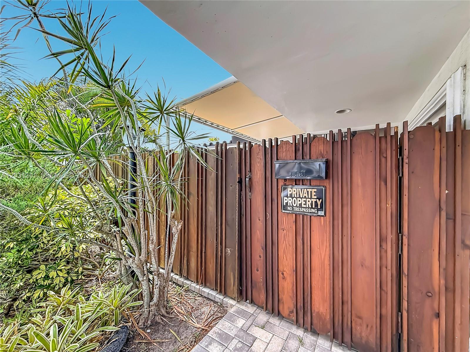 A wooden fence with a mailbox and a private property sign stands beside a plant — 2216 NE 18th Ave, Wilton Manors FL 33305, WILTON MANORS, FL