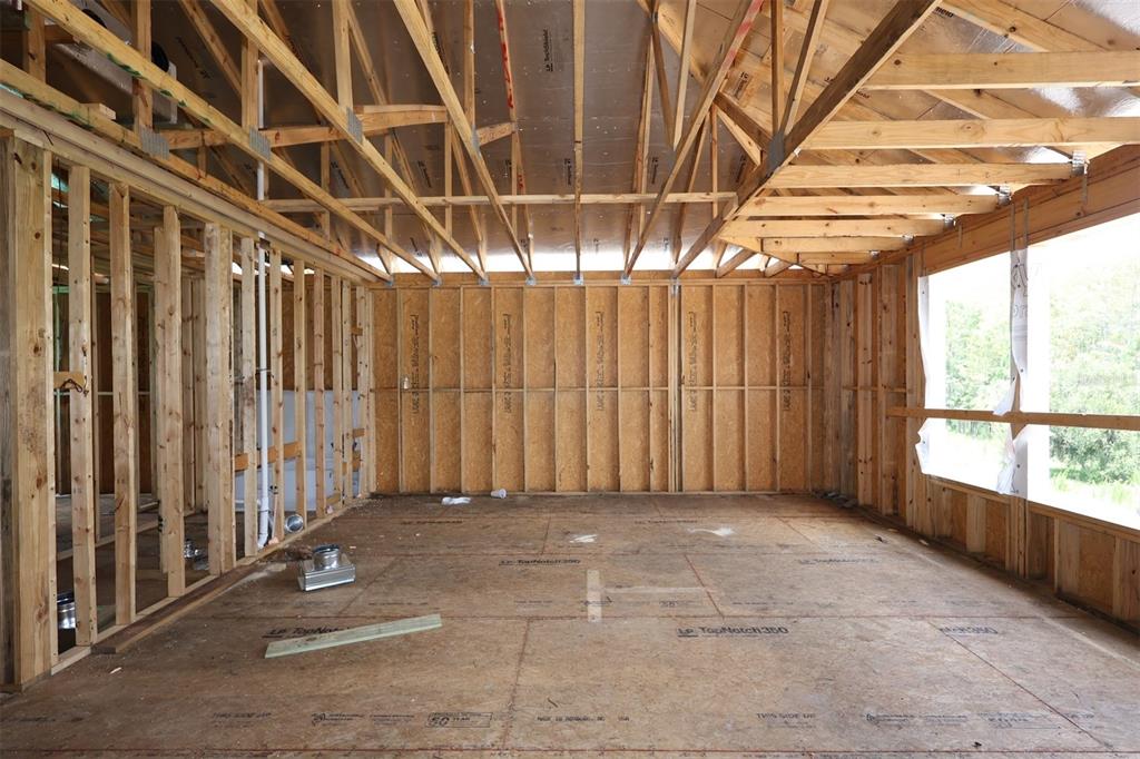 An unfinished room with exposed wooden wall studs, roof trusses, and subflooring under construction — 3011 SOLACE WAY, ORLANDO, FL