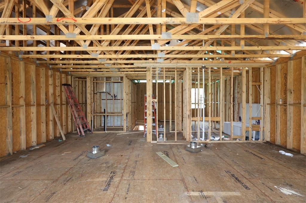 An interior view of a house under construction showing exposed wooden wall studs and trusses — 3011 SOLACE WAY, ORLANDO, FL