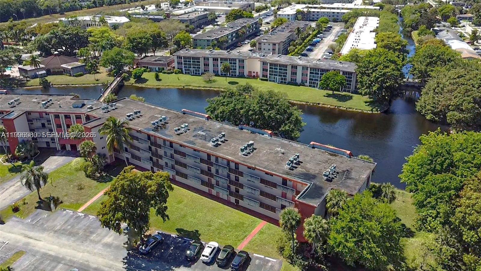 An aerial view shows a multi-story apartment complex situated next to a canal — 1103 NW 58th Ter # 116, Sunrise FL 33313, SUNRISE, FL