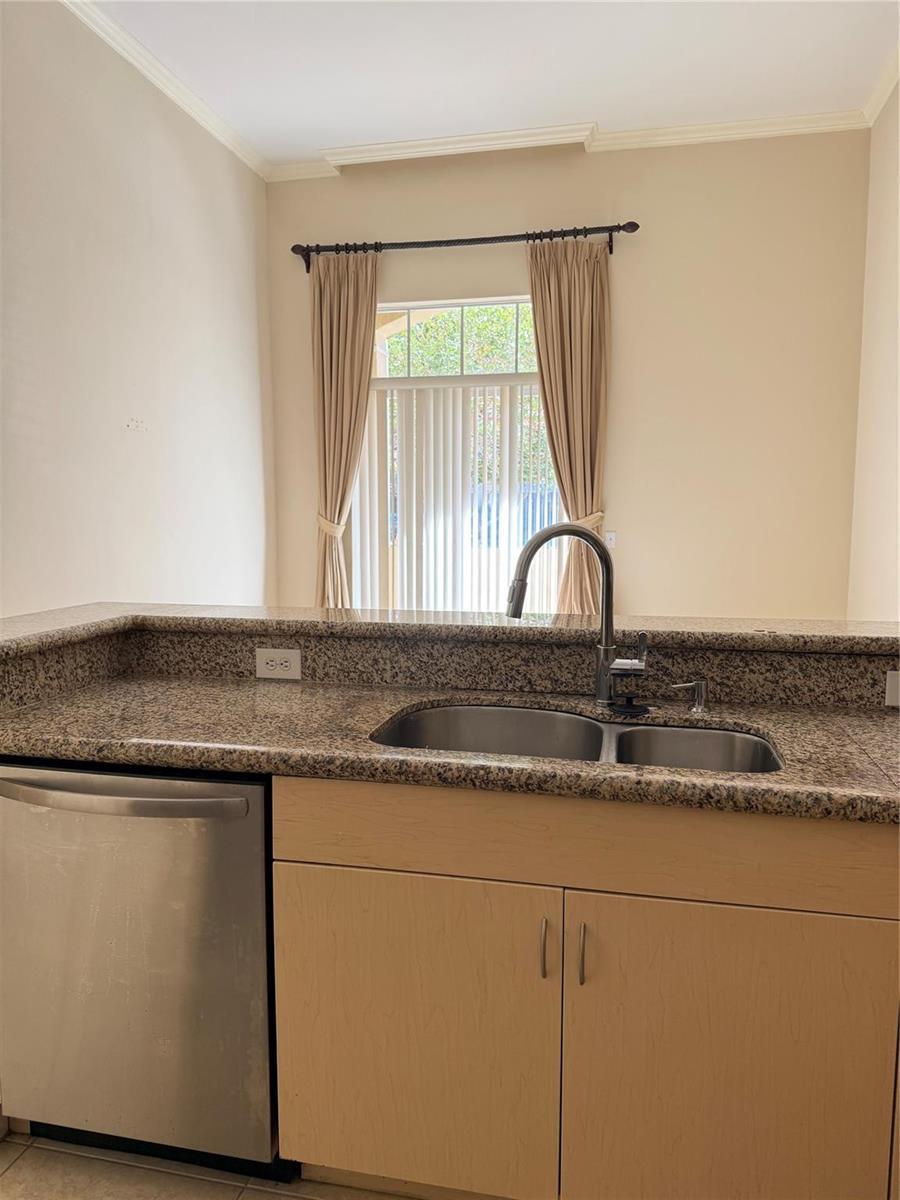 A kitchen sink with a granite countertop and stainless steel faucet sits before a window — 16102 Emerald Estates Drive # 103, Weston FL 33331, WESTON, FL