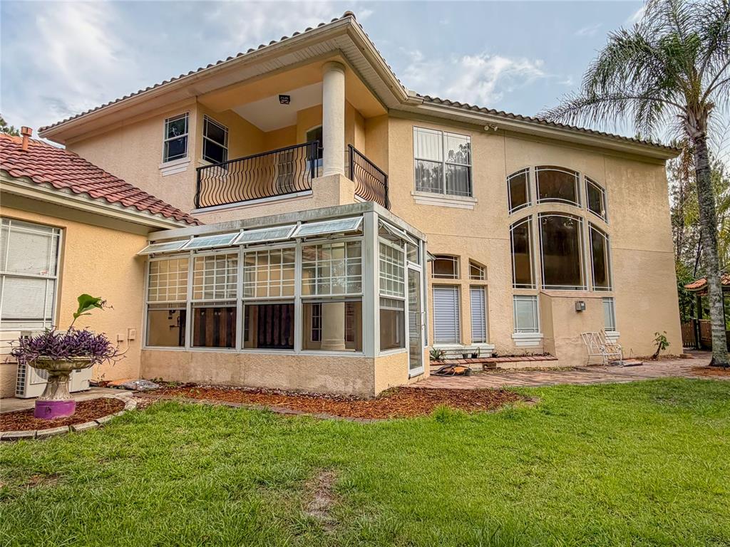 The exterior of a two-story stucco house features a sunroom, balcony, and arched windows — 779 E CHAPMAN ROAD, OVIEDO, FL