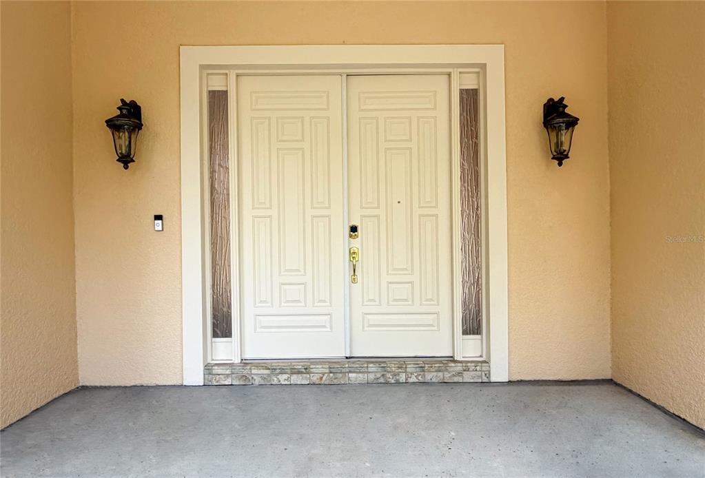 A double front door with sidelights is centered on a covered concrete porch — 779 E CHAPMAN ROAD, OVIEDO, FL