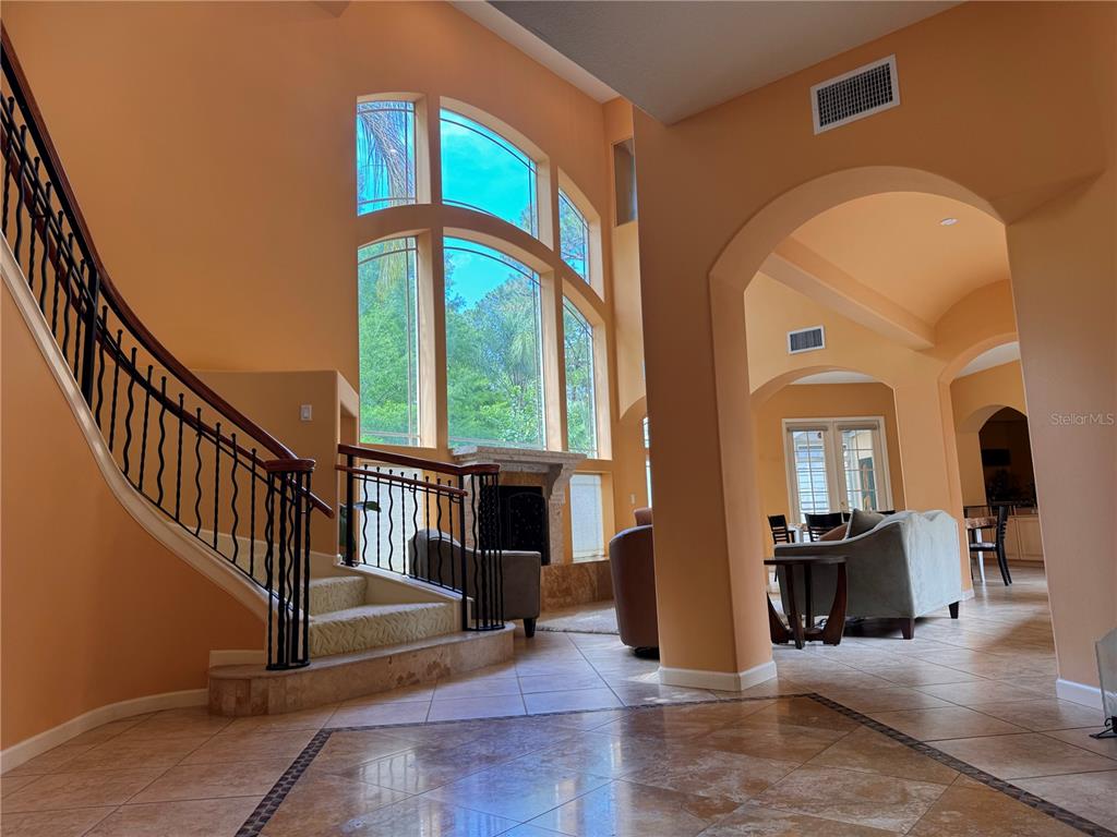 A grand foyer features a curved staircase, tile flooring, and a two-story arched window — 779 E CHAPMAN ROAD, OVIEDO, FL