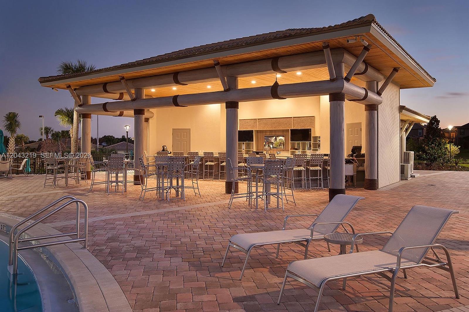 An outdoor covered patio features a bar area, dining tables, and lounge chairs by a pool — 655 Ocean Course # 0, Davenport FL 33896, DAVENPORT, FL
