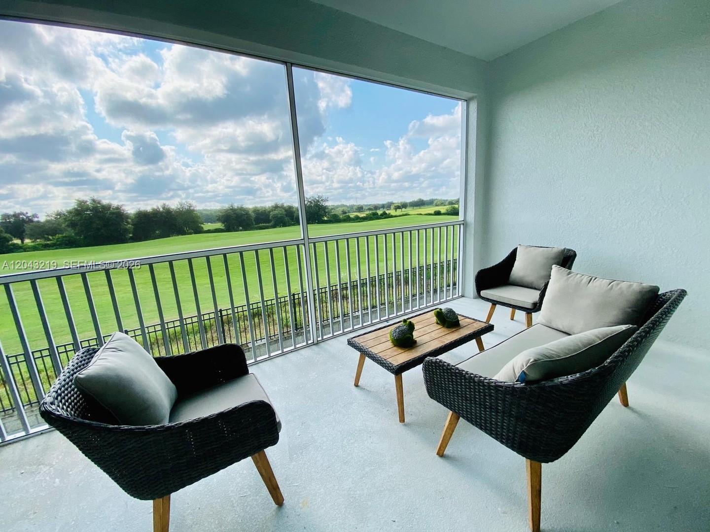 A screened-in balcony features wicker furniture and a view of a grassy golf course — 655 Ocean Course # 0, Davenport FL 33896, DAVENPORT, FL