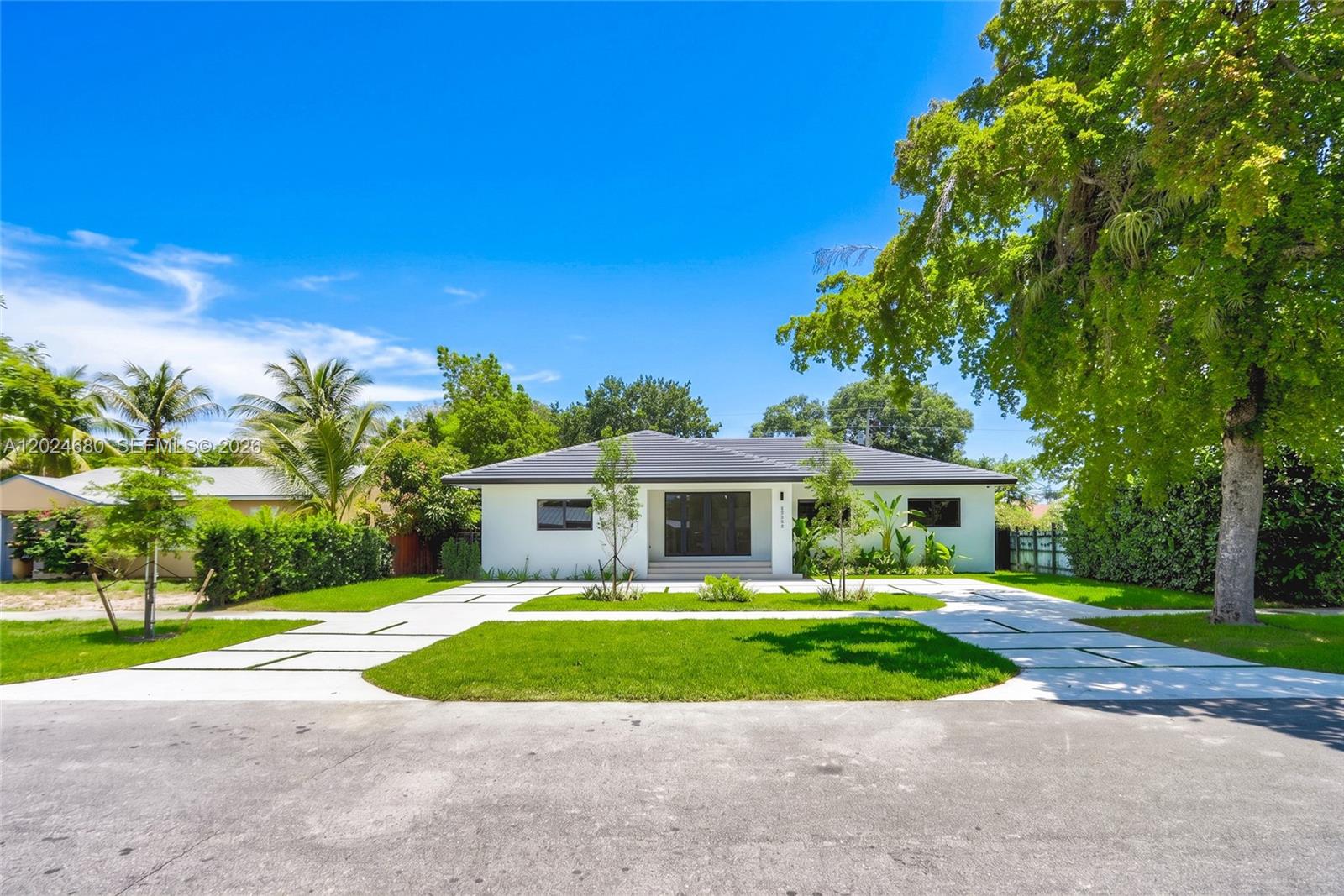 A white single-story house with a dark roof and a paved driveway sits on a lawn — 6853 S Waterway Dr, Miami FL 33155, MIAMI, FL