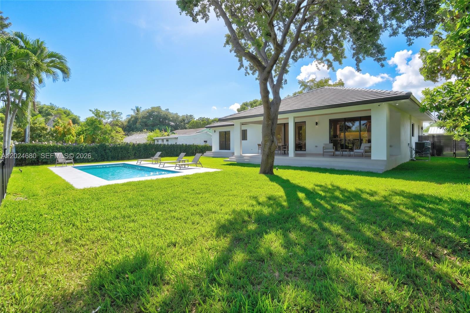 A backyard features a swimming pool, a grassy lawn, and a white house with a patio — 6853 S Waterway Dr, Miami FL 33155, MIAMI, FL
