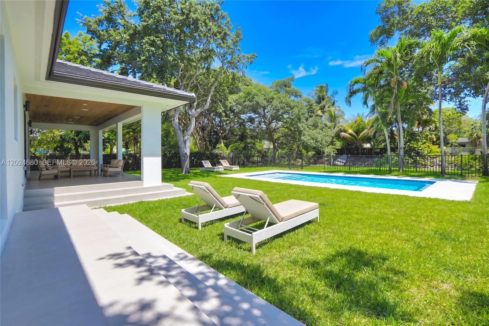 A backyard features a swimming pool, a covered patio, and several lounge chairs on grass — 6853 S Waterway Dr, Miami FL 33155, MIAMI, FL