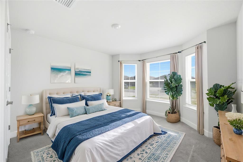 A bedroom features a queen bed, bay windows, two potted plants, and light-colored furniture — 4355 SUTHERLAND STREET, SPRING HILL, FL