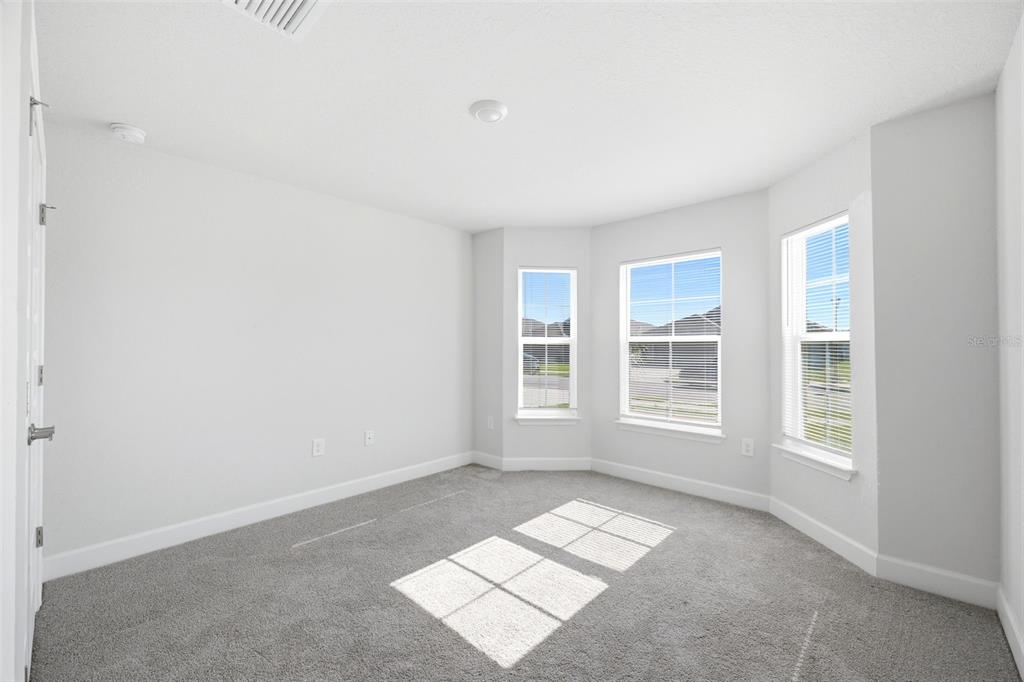 An empty room with gray carpet, white walls, and a bay window — 4355 SUTHERLAND STREET, SPRING HILL, FL