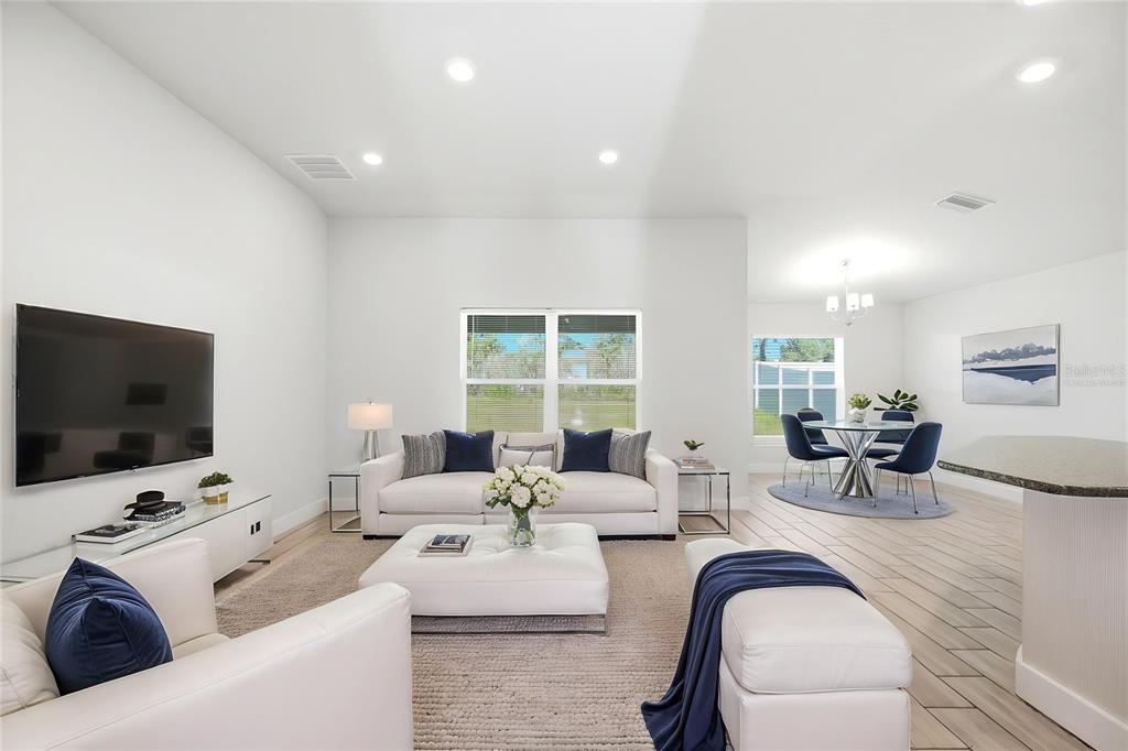 A bright living room features white sofas, a central ottoman, and an adjacent dining area — 4355 SUTHERLAND STREET, SPRING HILL, FL